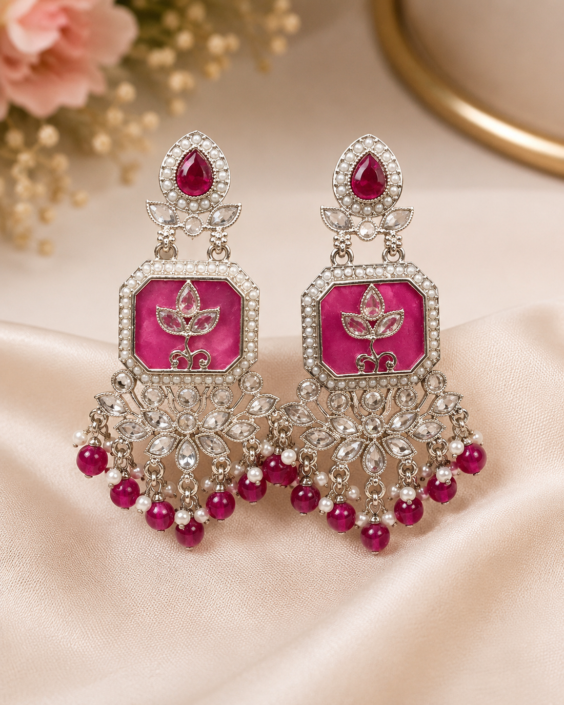 A woman wearing a large green and silver-toned traditional Indian jhumka earring, shown in a close-up portrait against a soft beige background.