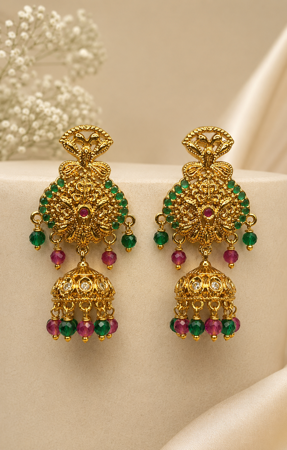 Gold ruby emerald round filigree arabesque chandelier stud with CZ centre dome jhumka and ruby emerald crystal bead drops on cream display