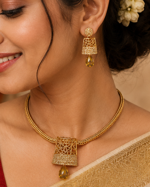 A woman wearing a traditional Indian saree with a deep red blouse and a cream-colored saree with a gold zari border. She is styled with a gold necklace, matching gold earrings, and white jasmine flowers in her hair, set against a warm, decorated background.