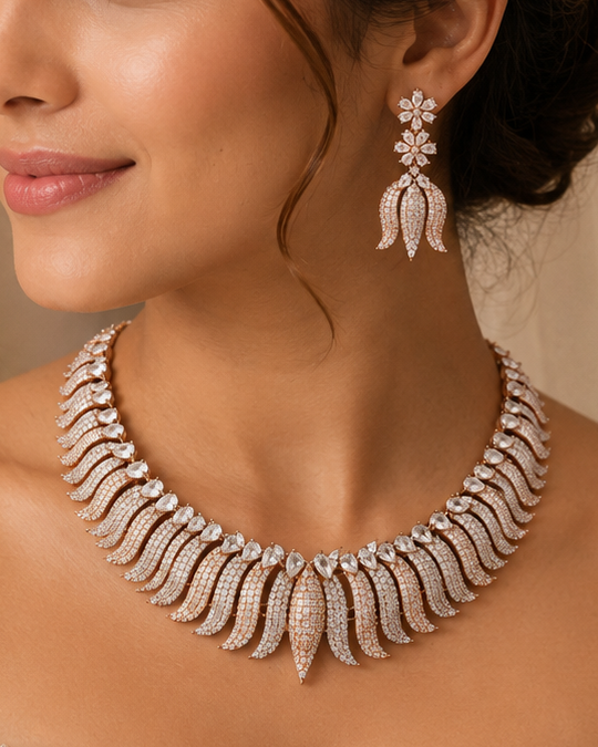 A woman in a white lace bridal gown wearing a silver-toned statement necklace and matching drop earrings, photographed in a softly lit indoor setting.