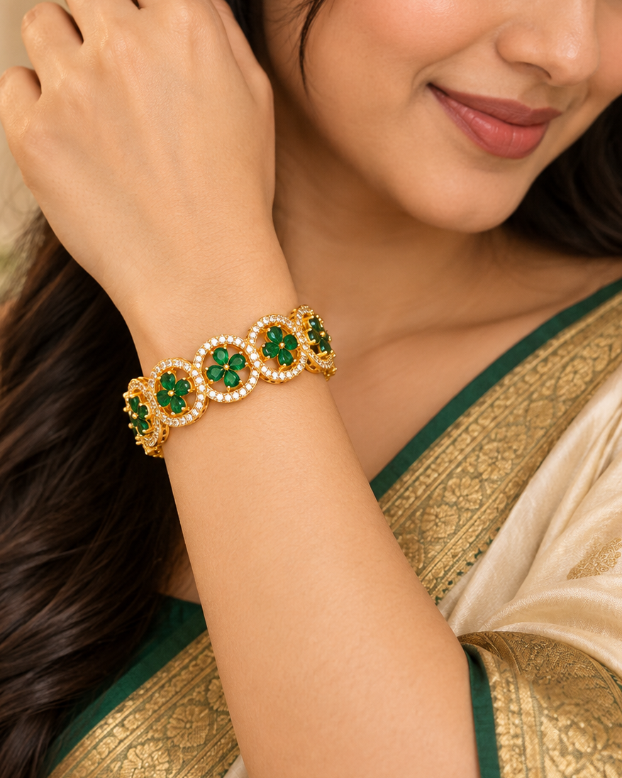 A woman wearing a gold and green beaded bracelet with pearl-like accents, styled with a green and gold saree.