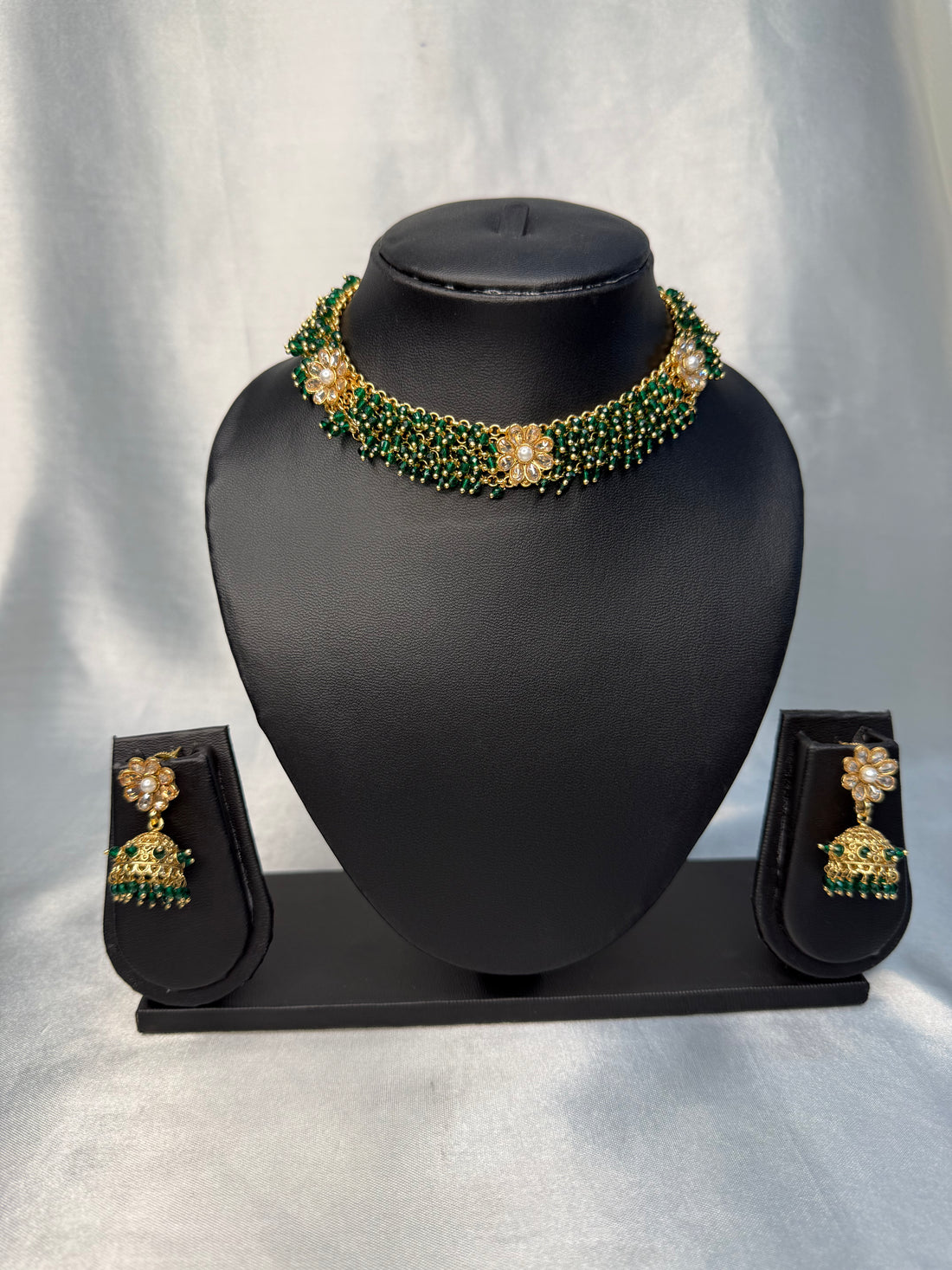 Jewelry set with necklace and earrings on a black mannequin bust against a white background