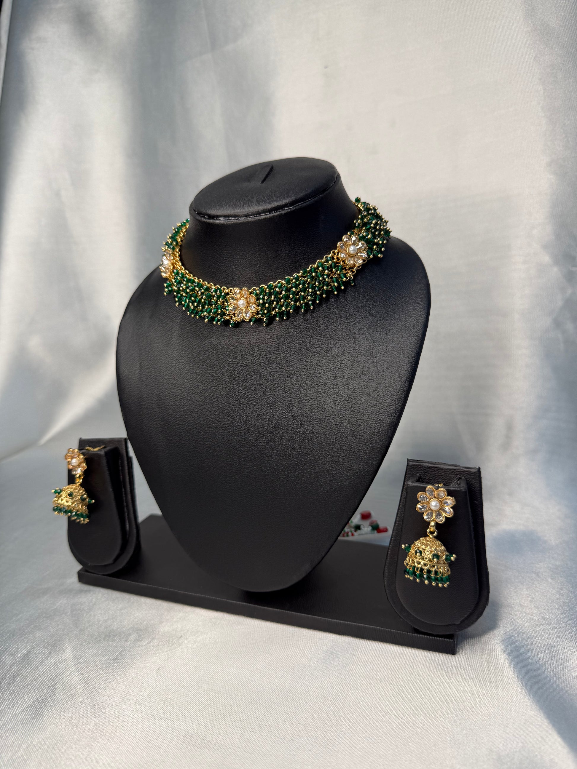 Jewelry set with necklace and earrings on a black stand against a white background