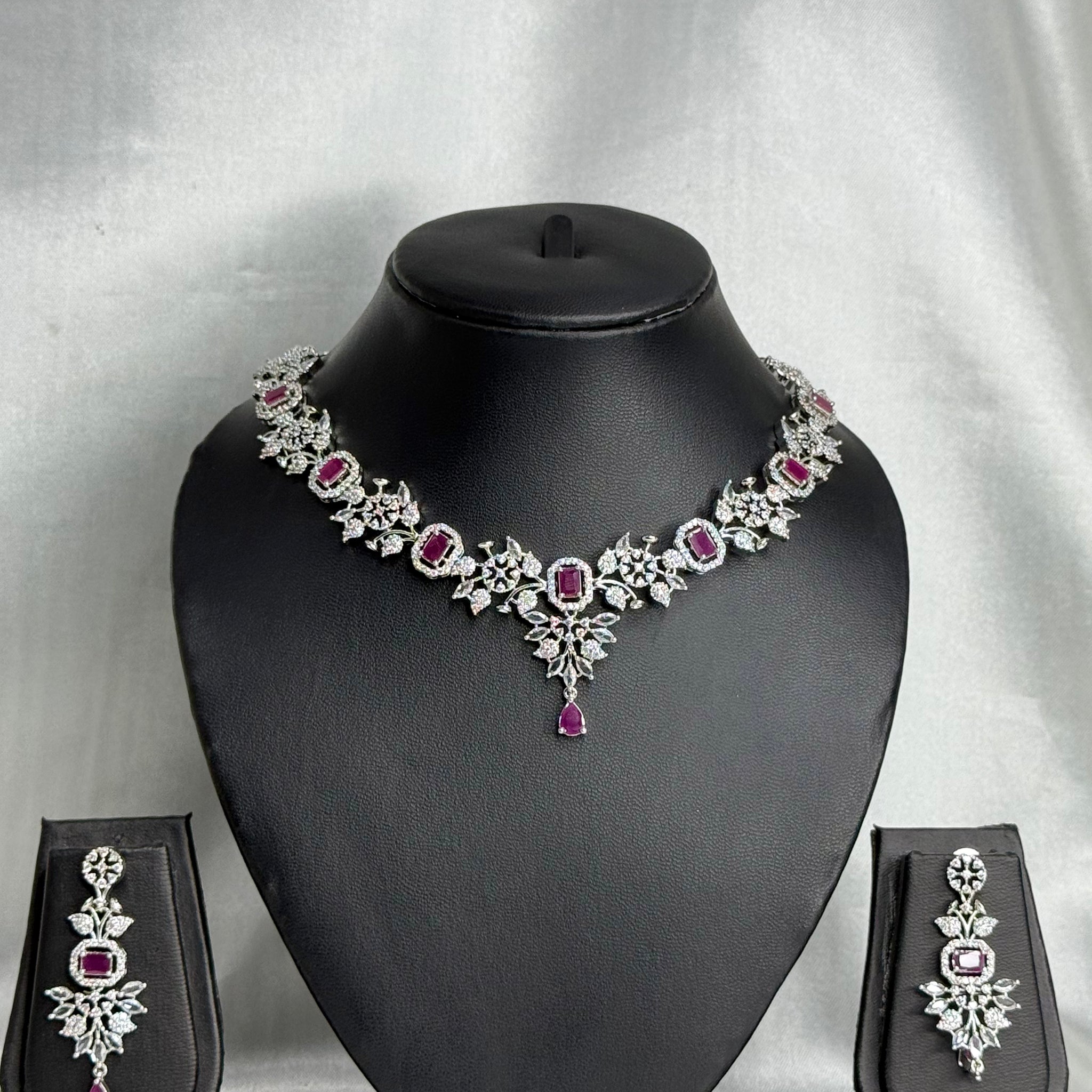 Jewelry set with necklace, earrings, and pouches on a black mannequin bust against a gray background.