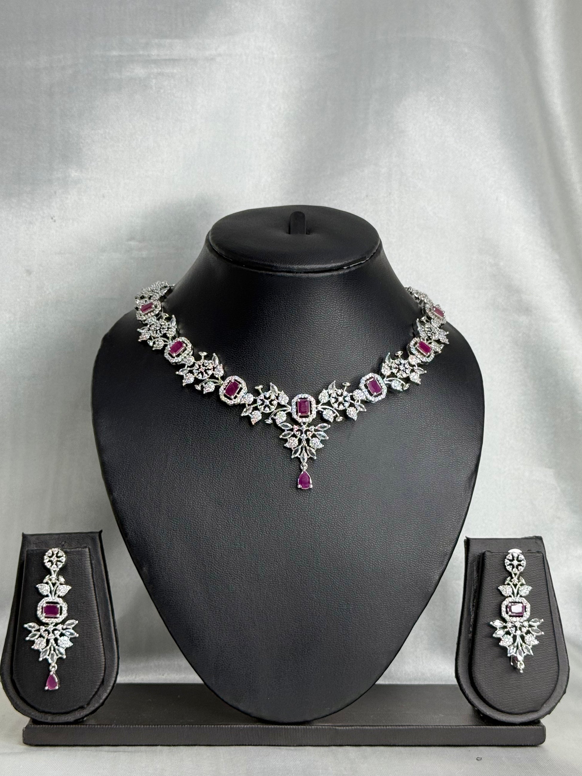 Jewelry set with necklace, earrings, and pouches on a black mannequin bust against a gray background.