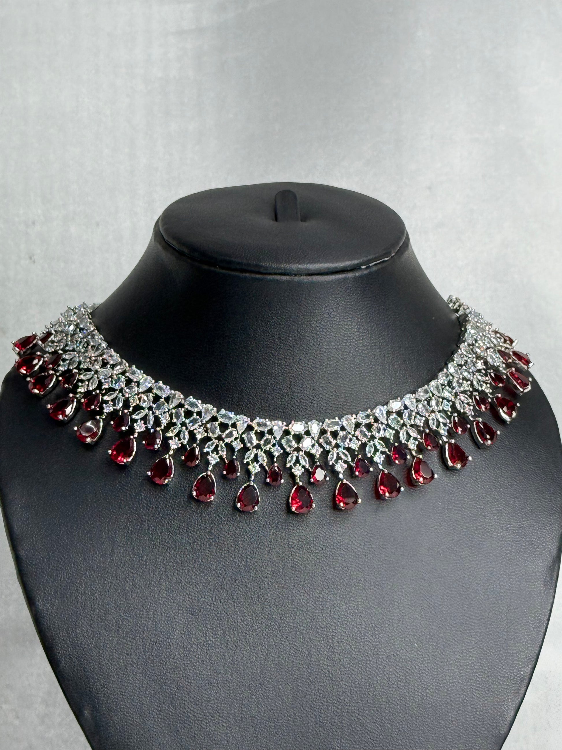 Elegant necklace with red gemstones on a black mannequin against a gray background
