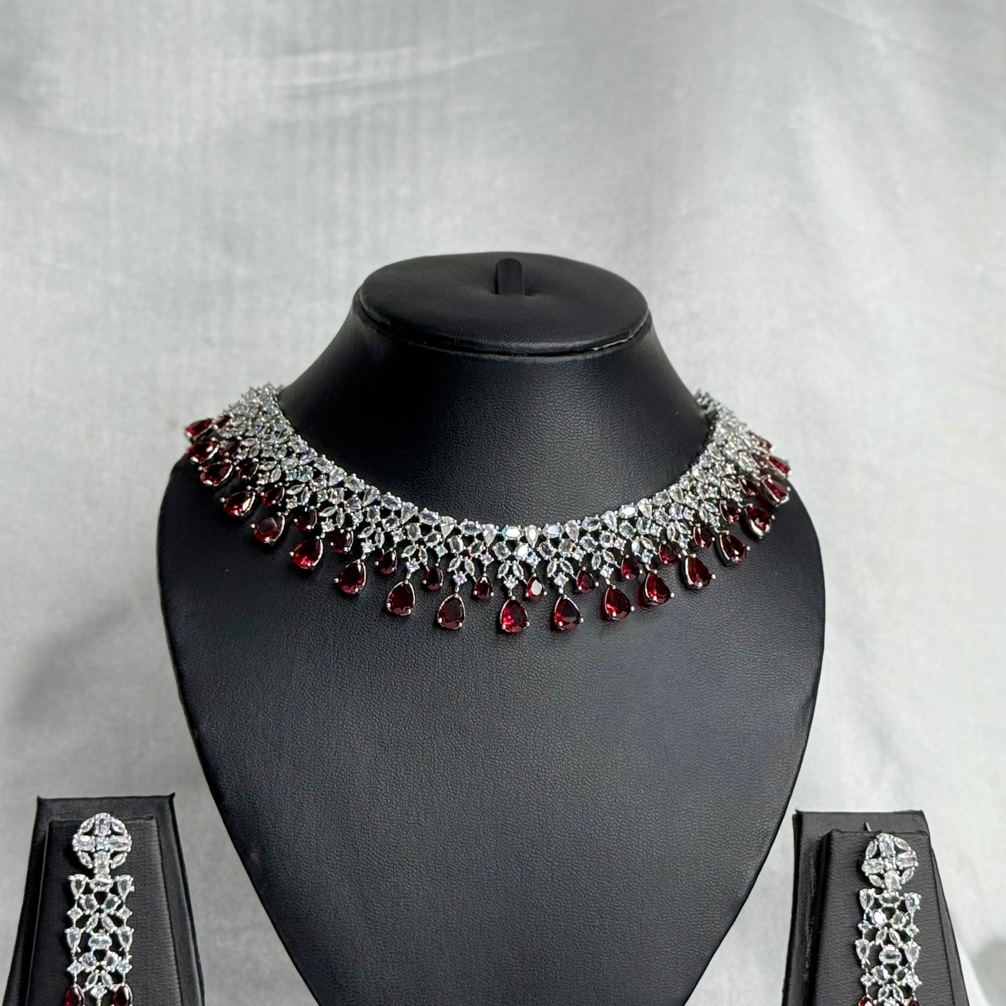 Jewelry set with necklace, earrings, and box on a gray background