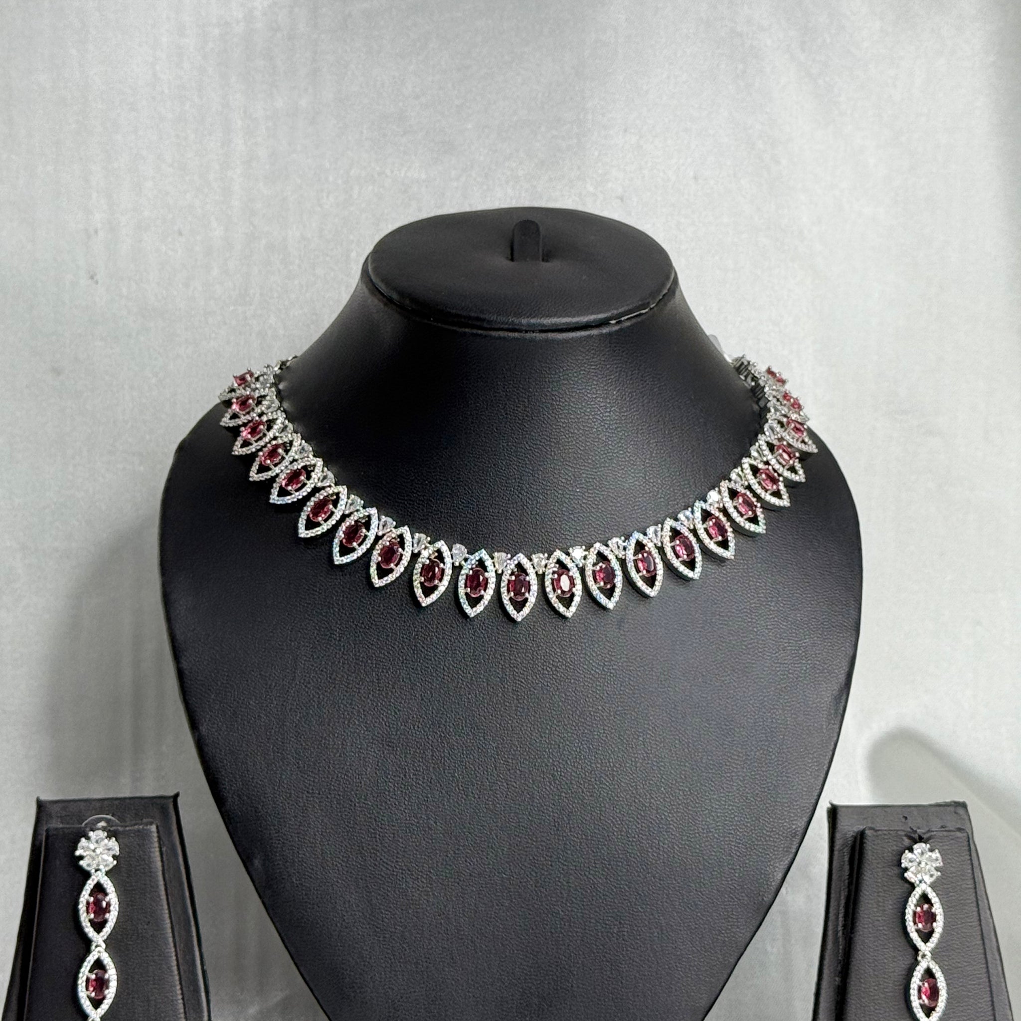 Jewelry set with necklace and earrings on a black mannequin bust against a gray background