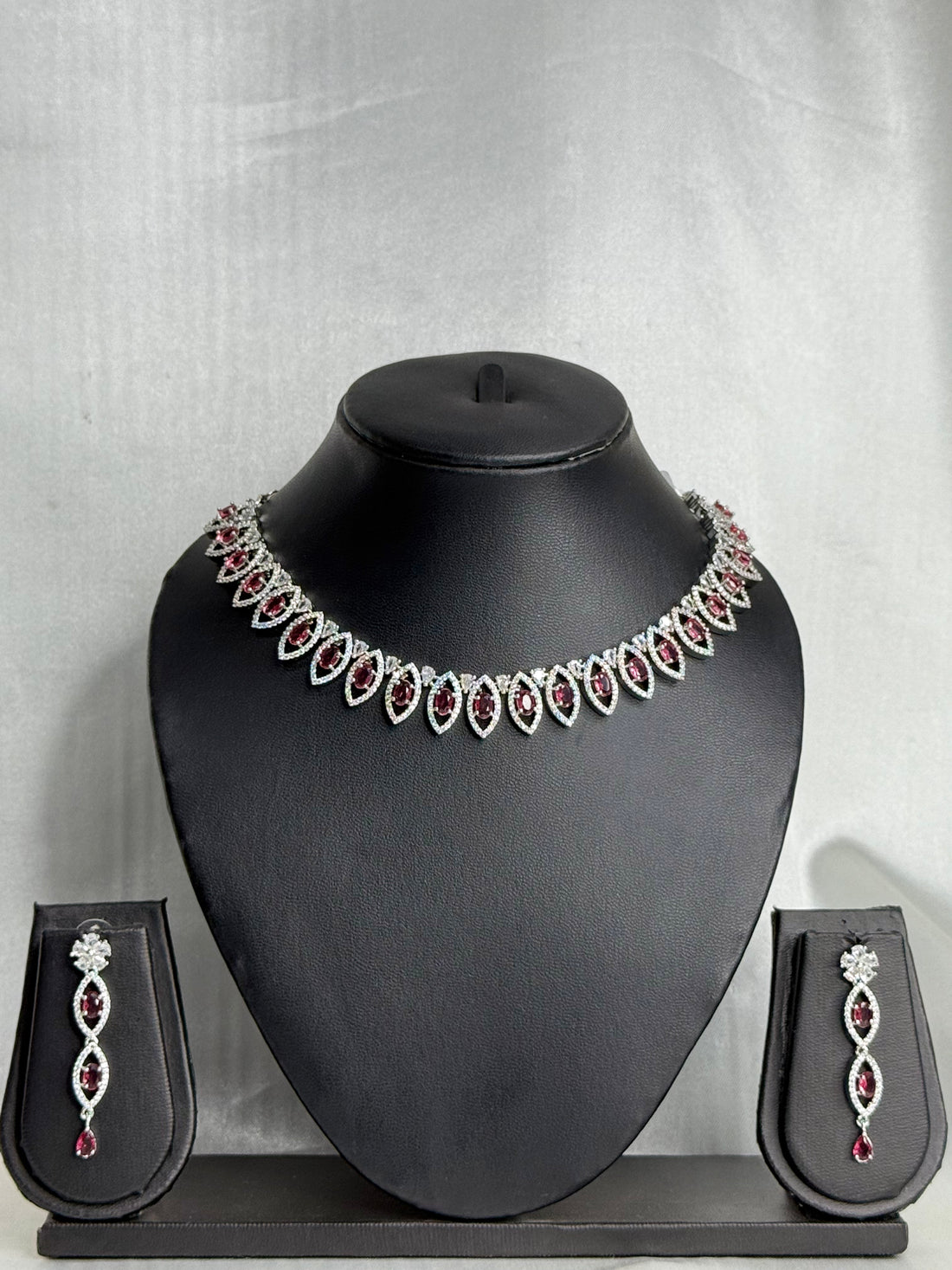 Jewelry set with necklace and earrings on a black mannequin bust against a gray background