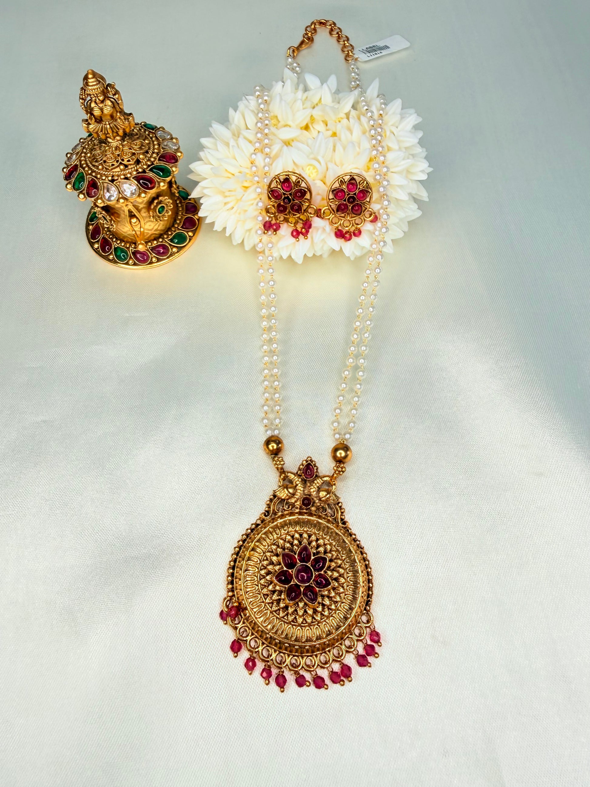 Gold necklace with floral pendant and matching earrings on a white background