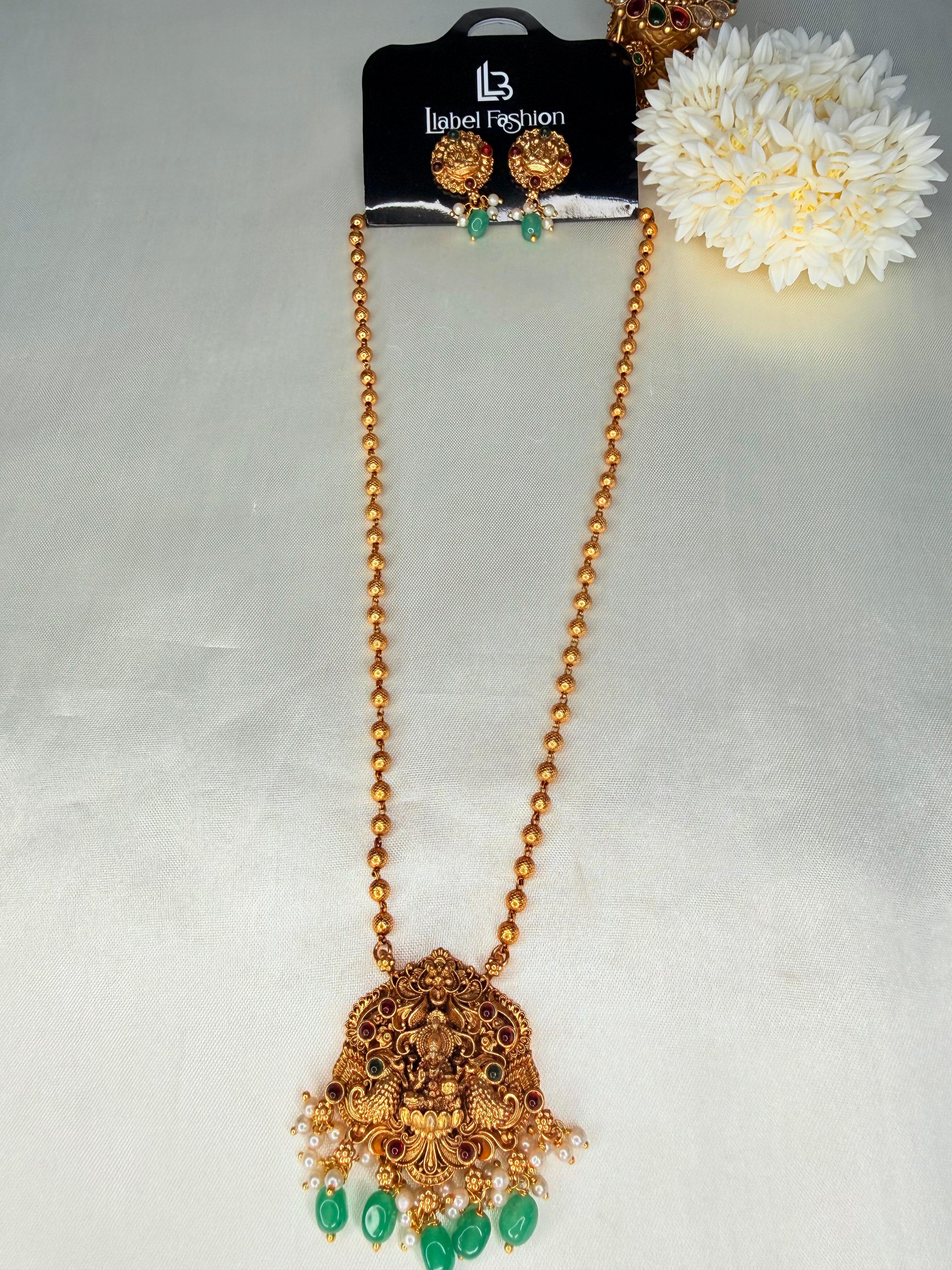 Gold necklace with green pendants on a gray background