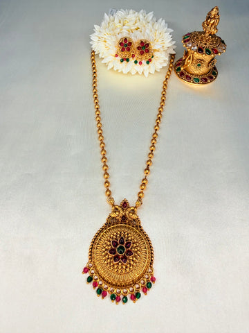 Gold necklace with floral hair accessory on a light gray background