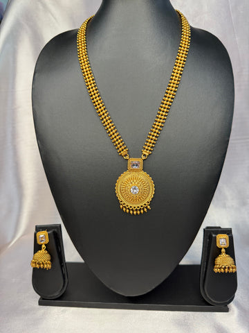 Gold necklace and earrings set on a black mannequin bust with a gray background