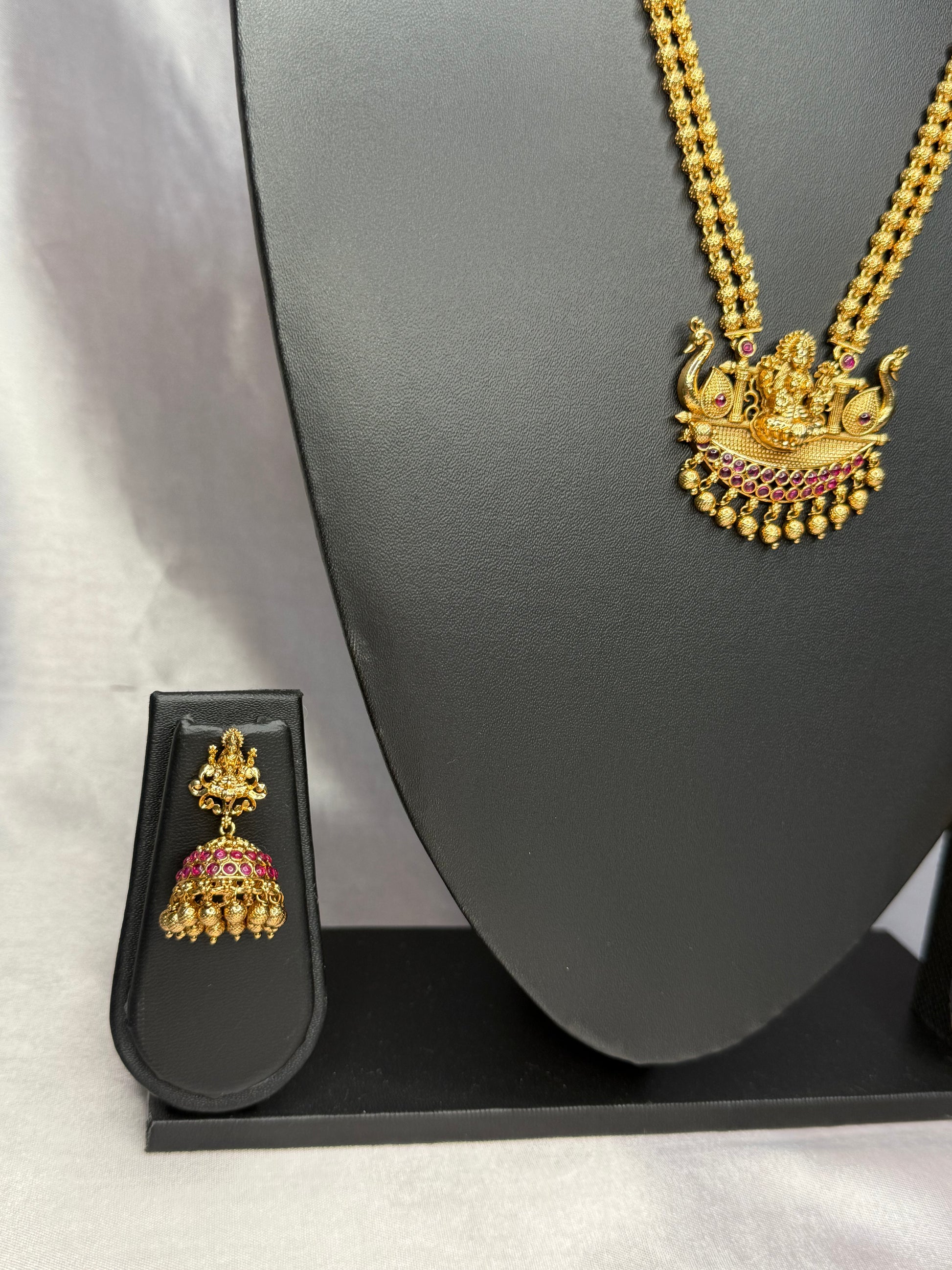 Gold necklace with pendant and earring set on a gray background