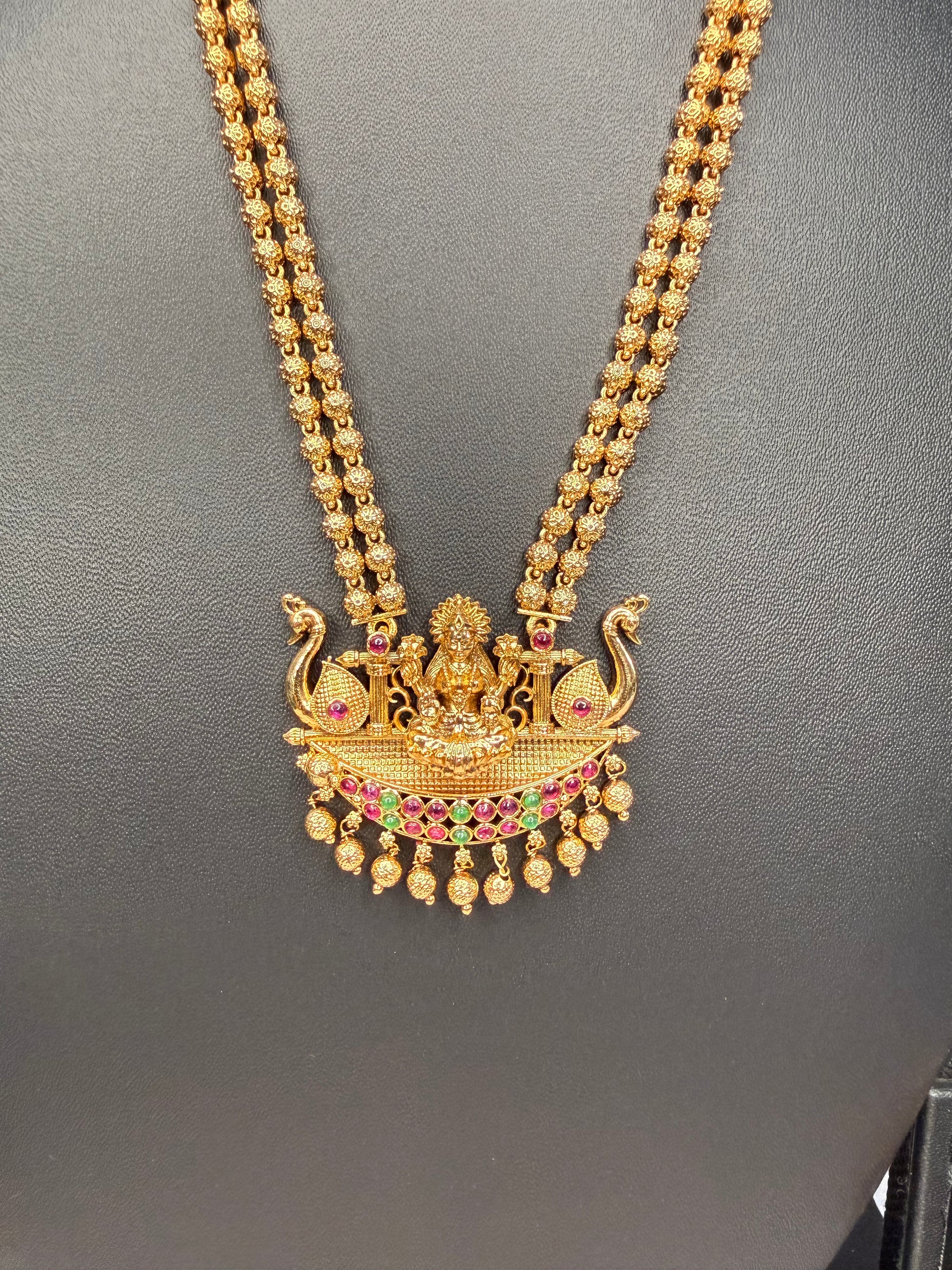 Gold necklace with a detailed pendant on a gray background