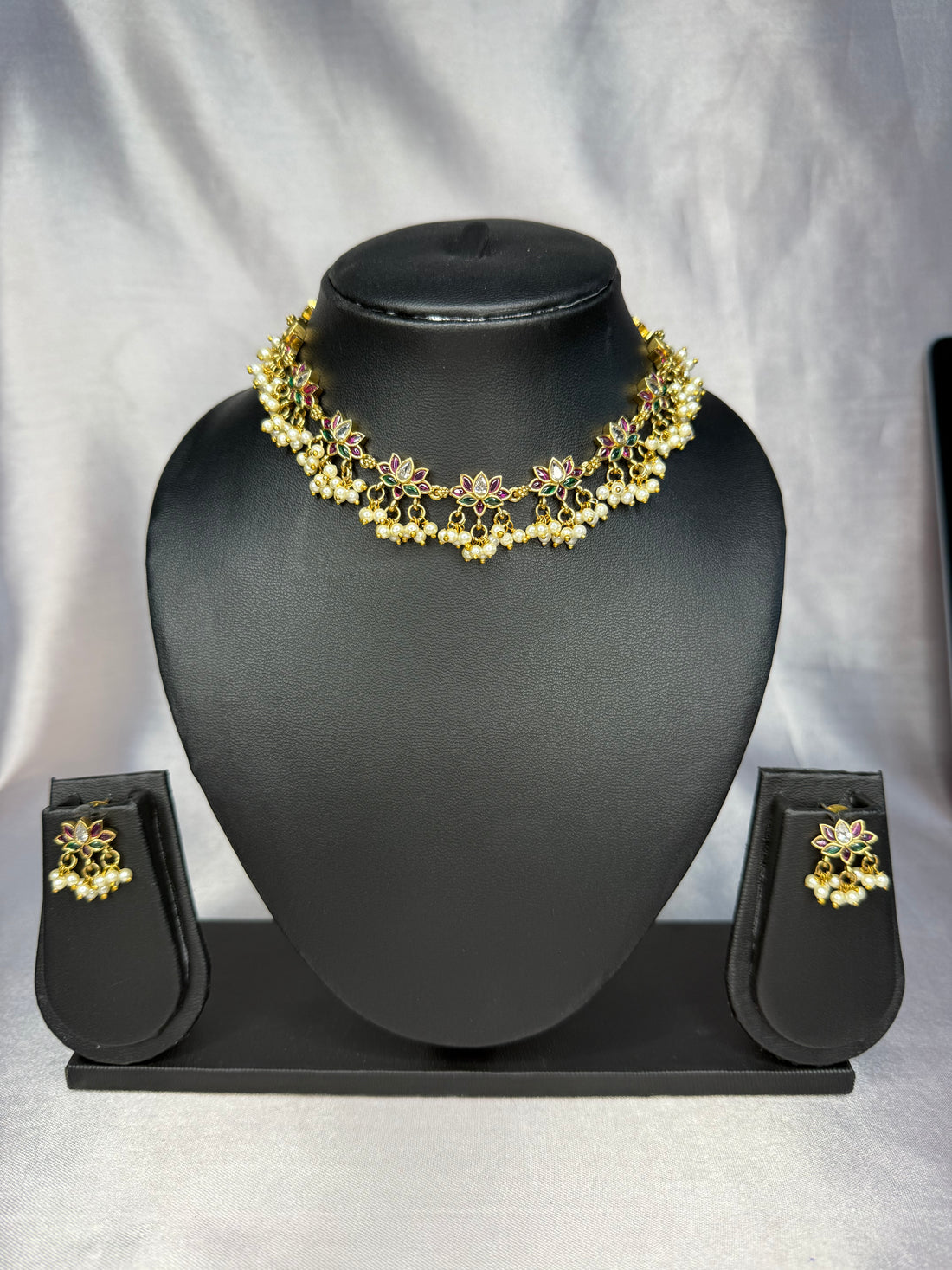 Gold jewelry set with necklace, earrings, and ring on a white background