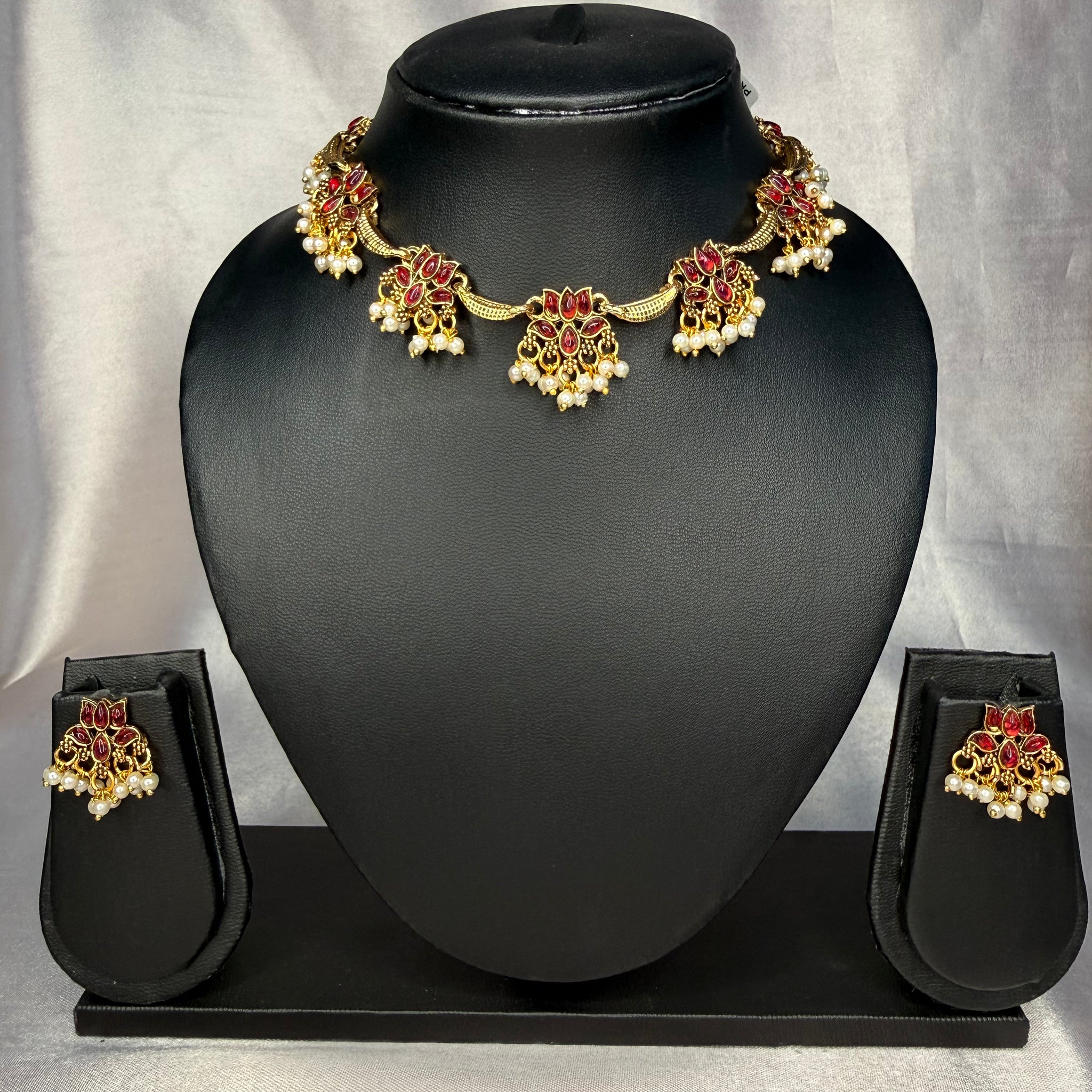 Jewelry set with necklace and earrings on a black mannequin bust against a gray background