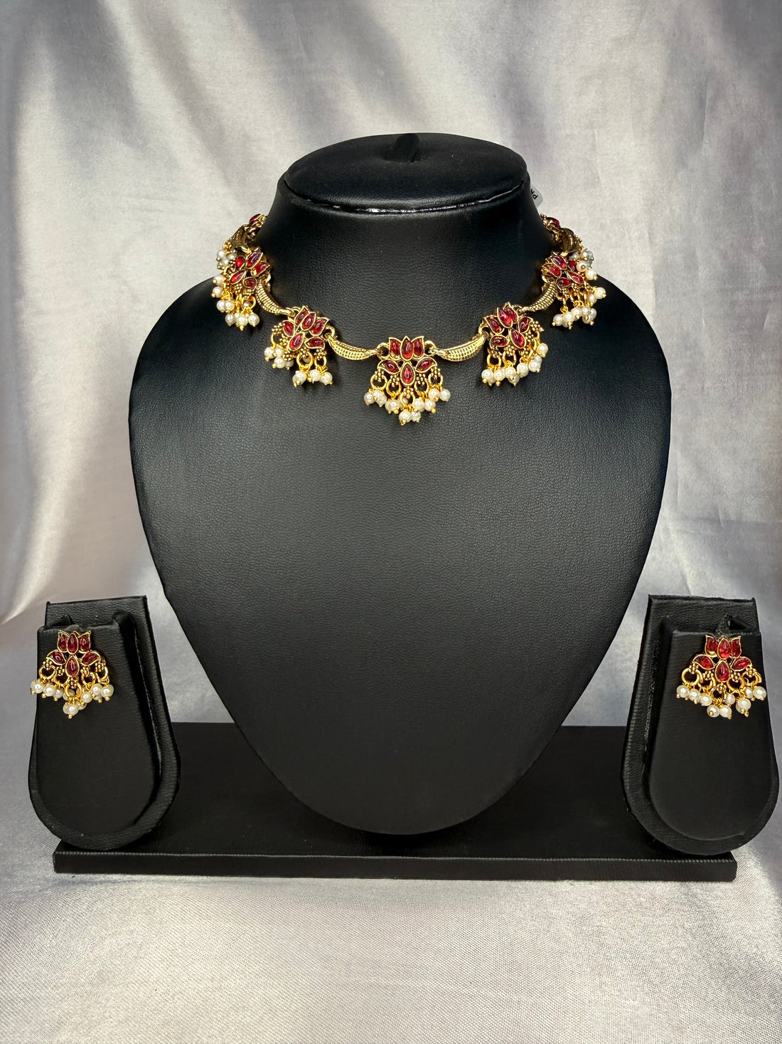 Jewelry set with necklace and earrings on a black mannequin bust against a gray background