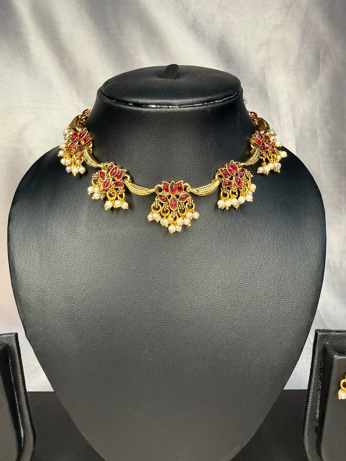 Jewelry set with necklace and earrings on a black mannequin bust against a gray background