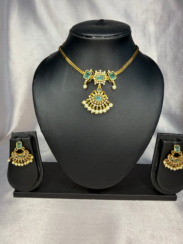 Gold and green jewelry set on a black mannequin bust with a plain background