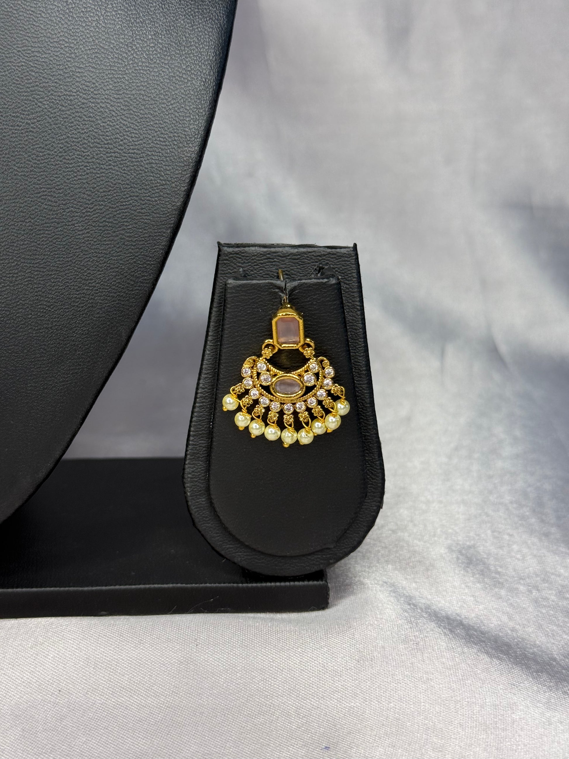 Gold and diamond pendant on a black stand against a gray background