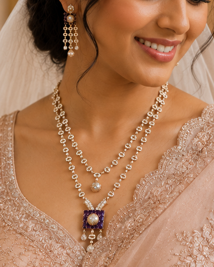 A smiling bride in a light peach-beige lace and sheer sari with a matching veil, wearing layered gold necklaces and holding a bouquet of white flowers in a church setting.