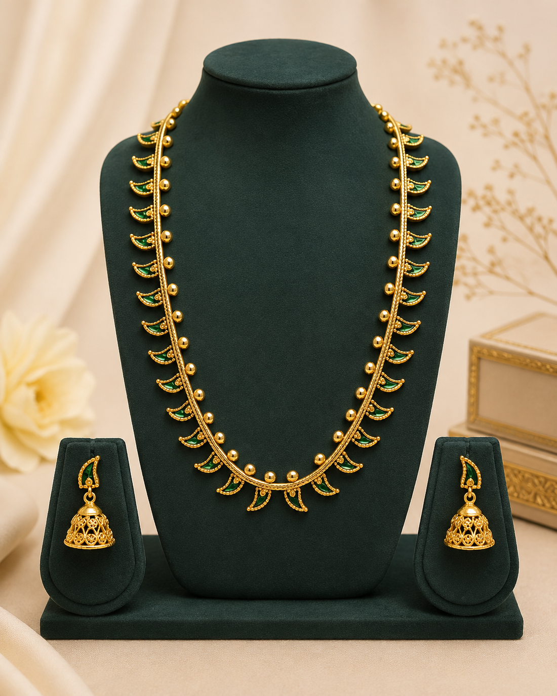 A woman wearing a cream-colored sari with gold borders and a matching gold necklace with green stone accents, styled with a white flower in her hair.