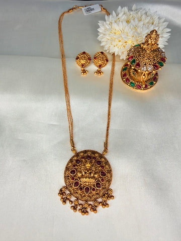 Gold necklace and earrings set with decorative flowers on a white fabric background