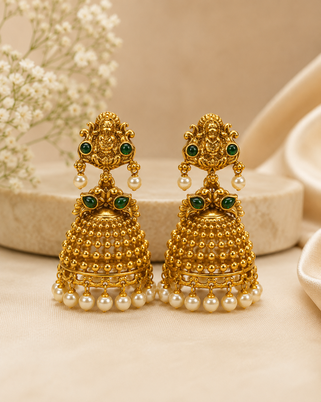 Antique gold Goddess Lakshmi emerald cabochon grand granule bead dome jhumka earrings with pearl drop connector and seed pearl drops on cream marble display