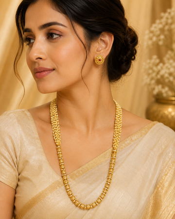 A woman wearing a traditional Indian gold necklace and matching gold earring, styled with a beige saree against a warm, elegant background.
