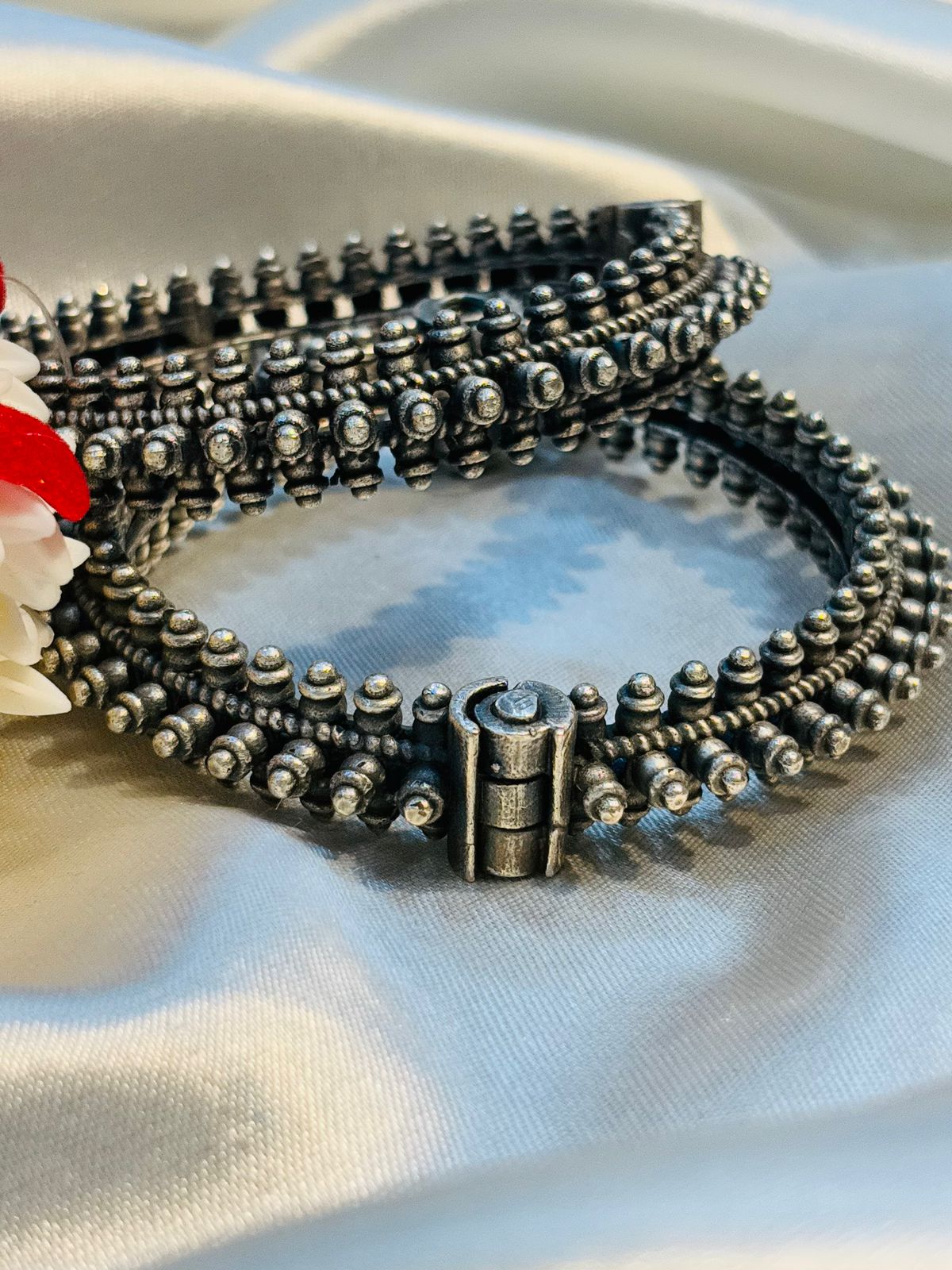 Stack of silver beaded bracelets on a white surface