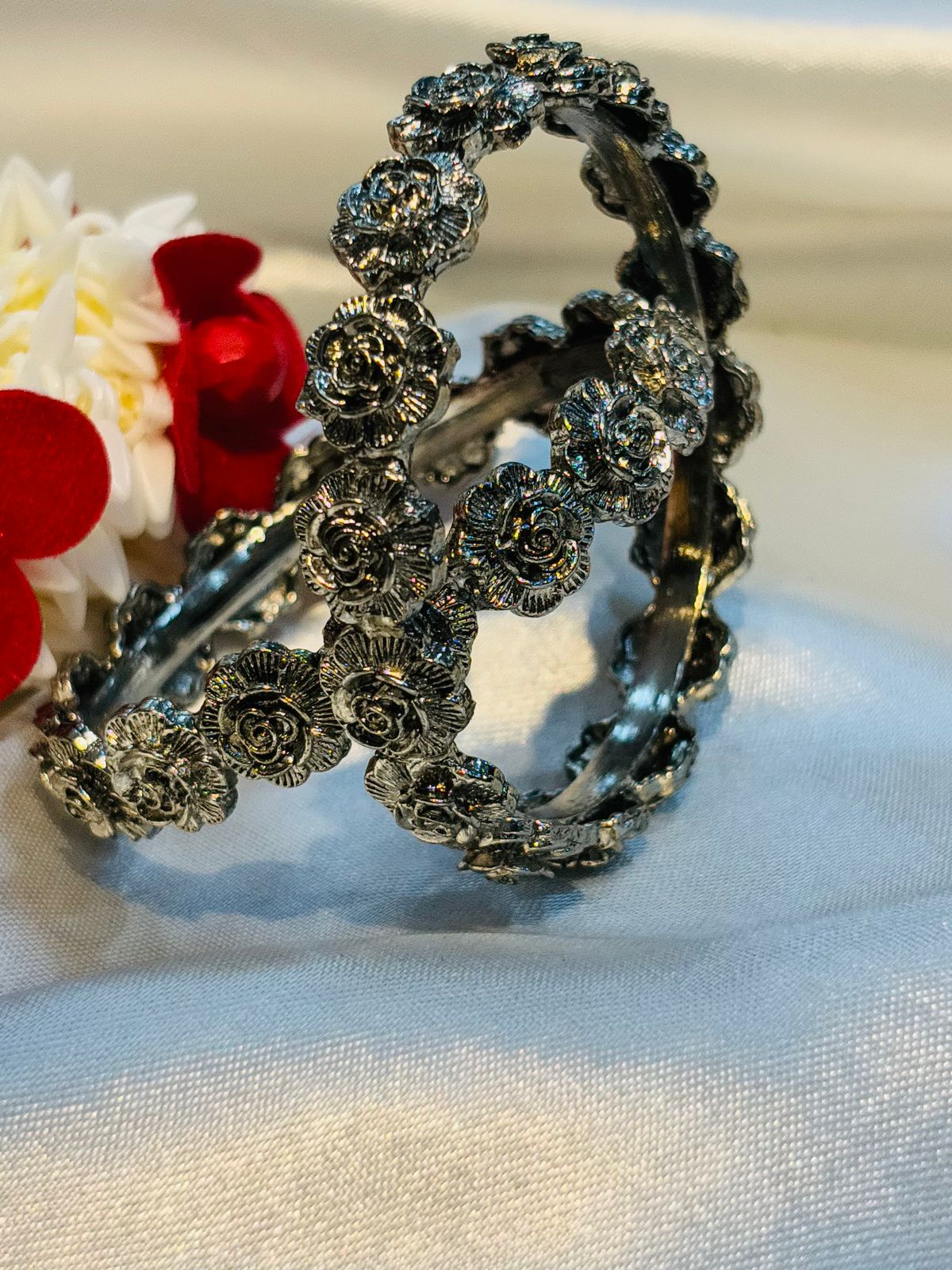 Silver floral headband on a white fabric background with a blurred cupcake in the background