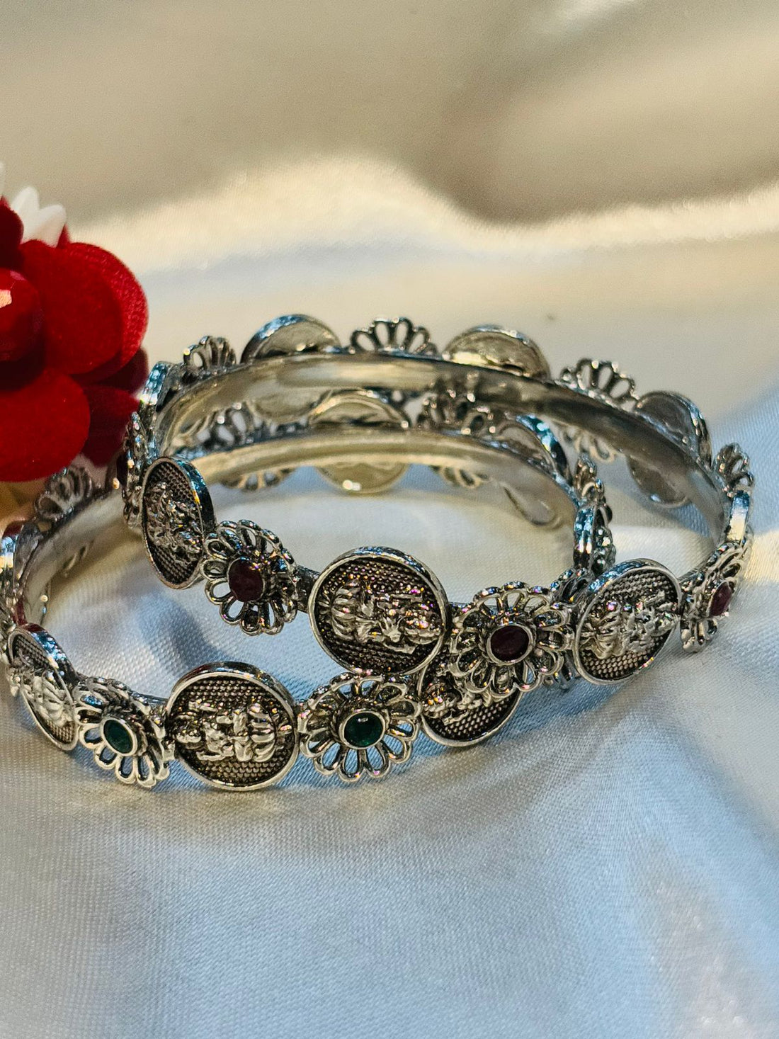 Silver bracelet with decorative elements on a white fabric background
