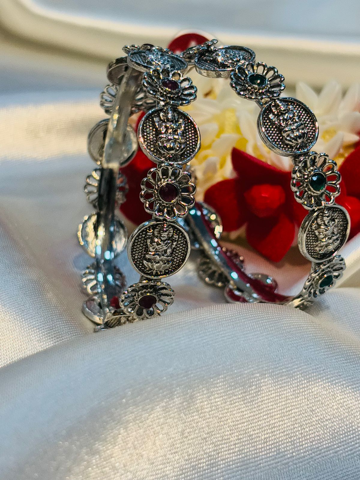 Silver bracelet with decorative elements on a white fabric background