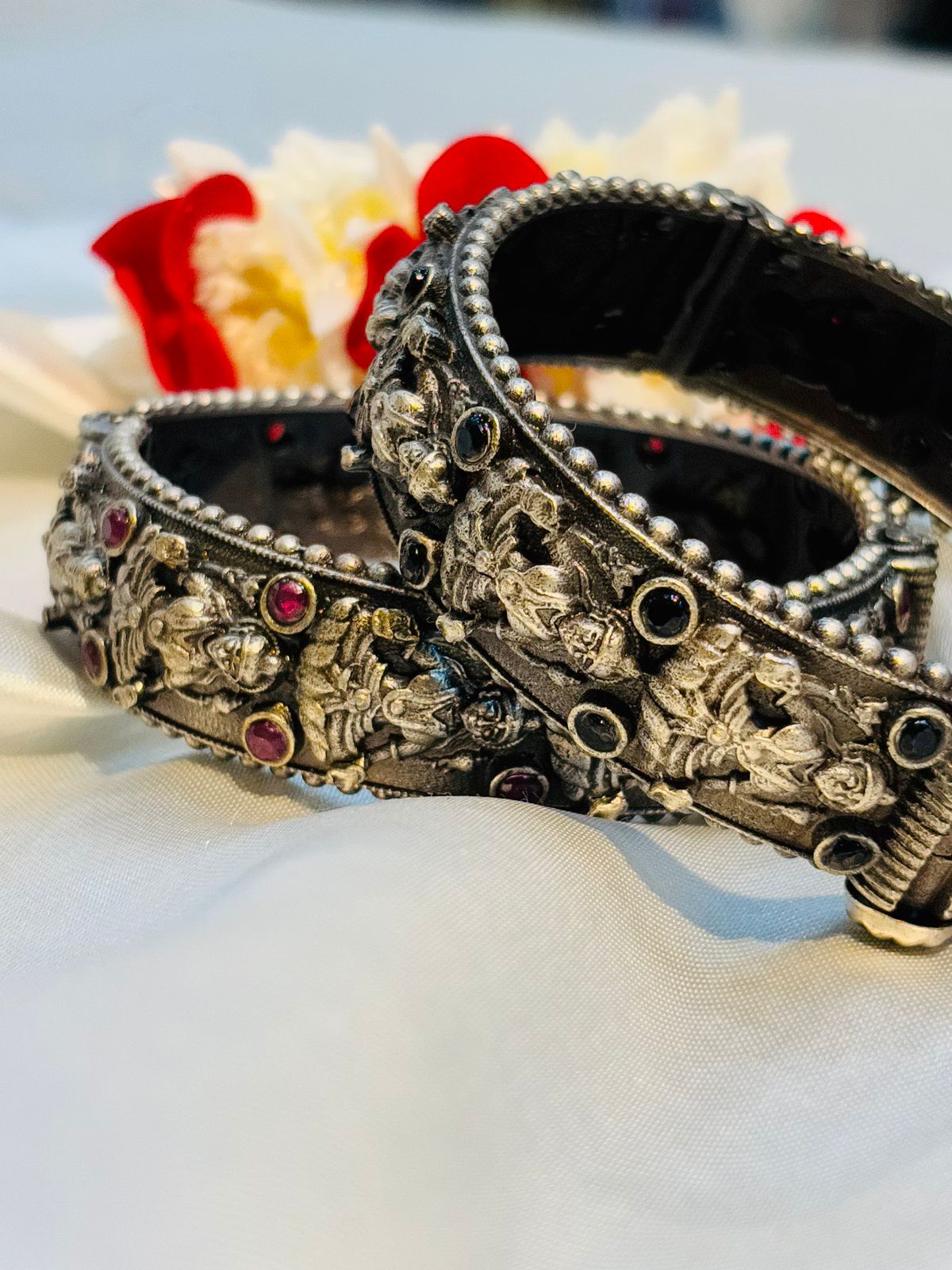 Decorative silver bangles with intricate designs on a white surface.