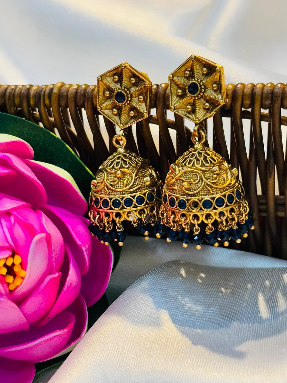 Gold and blue earrings on a white background with a pink flower.