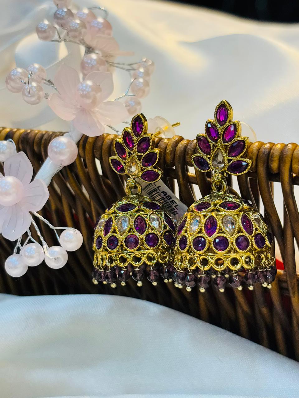 Gold and purple beaded earrings on a decorative background