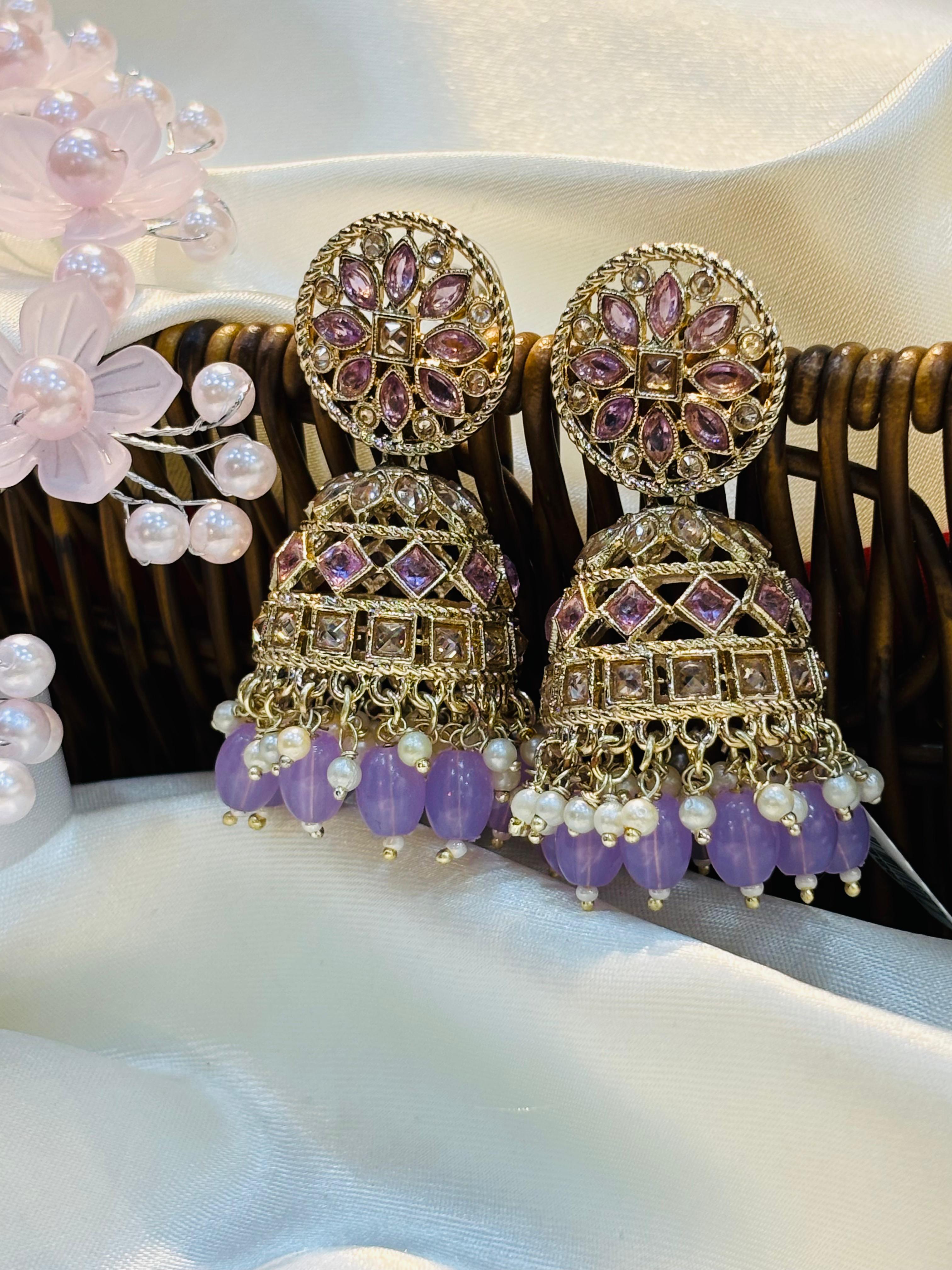 Ornate earrings with purple and gold details on a white surface