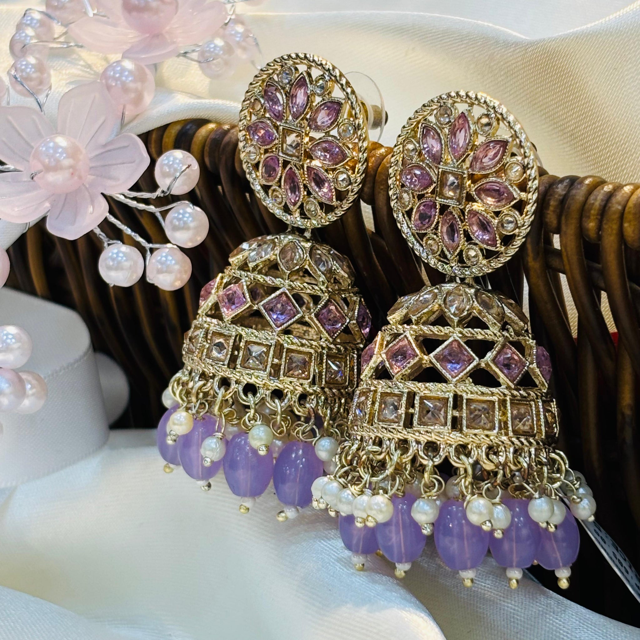 Ornate earrings with purple beads and gold accents on a white surface.