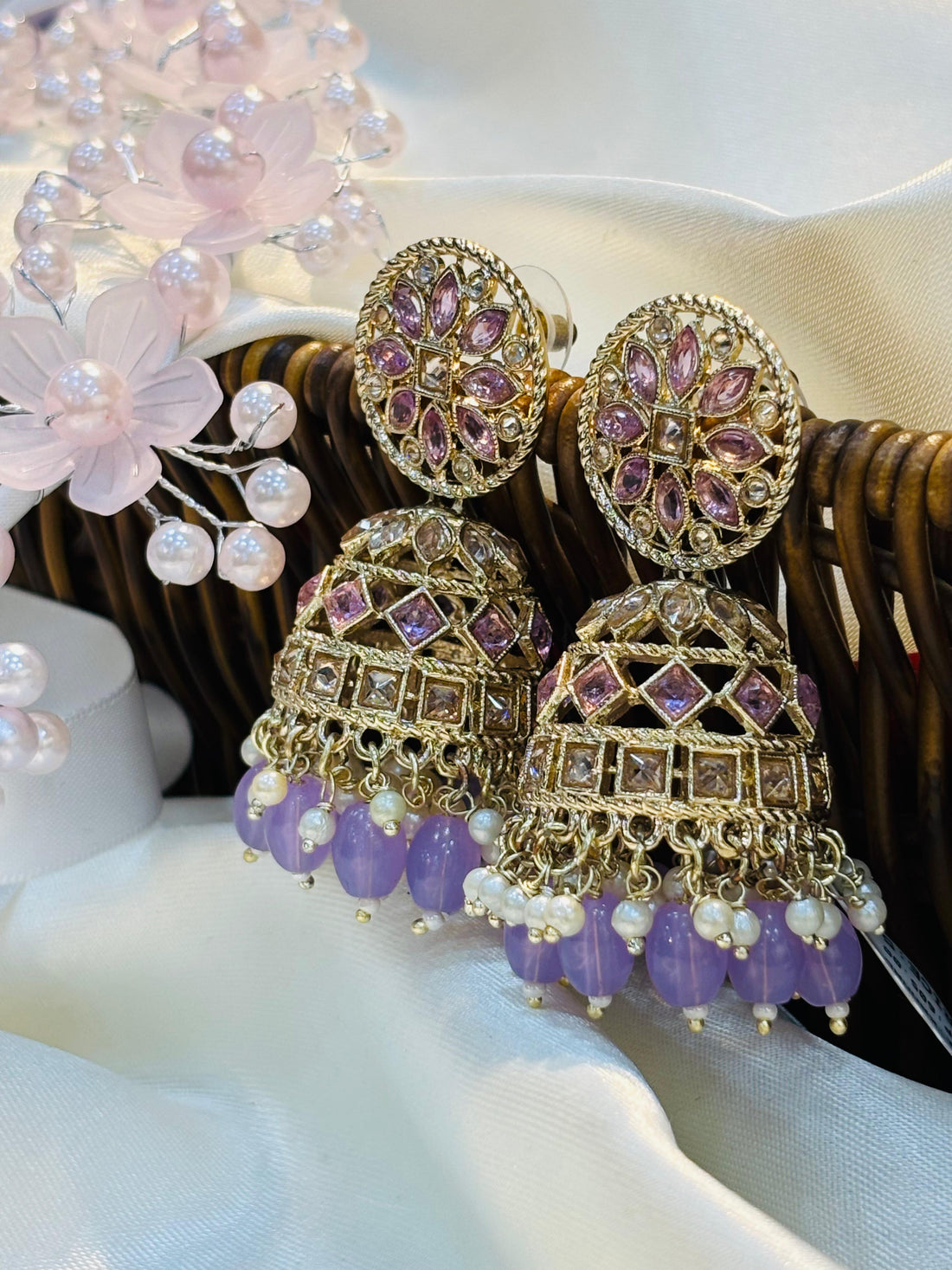 Ornate earrings with purple beads and gold accents on a white surface.
