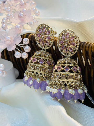 Ornate earrings with purple beads and gold accents on a white surface.