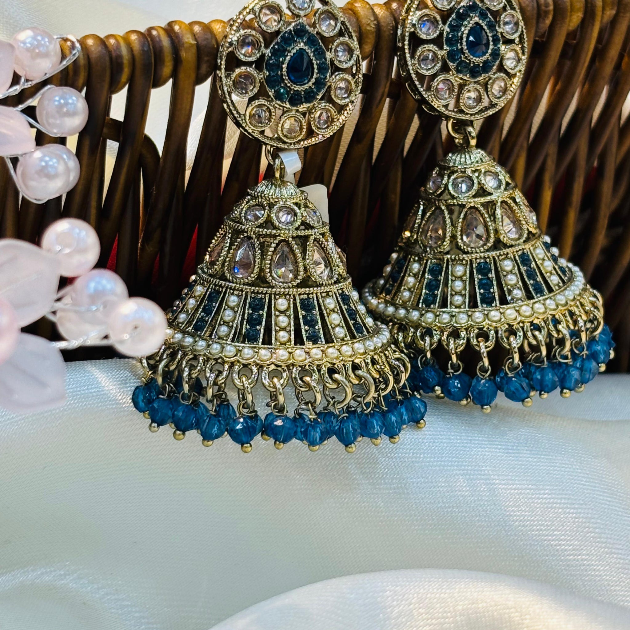 Ornate earrings with blue beads on a white surface