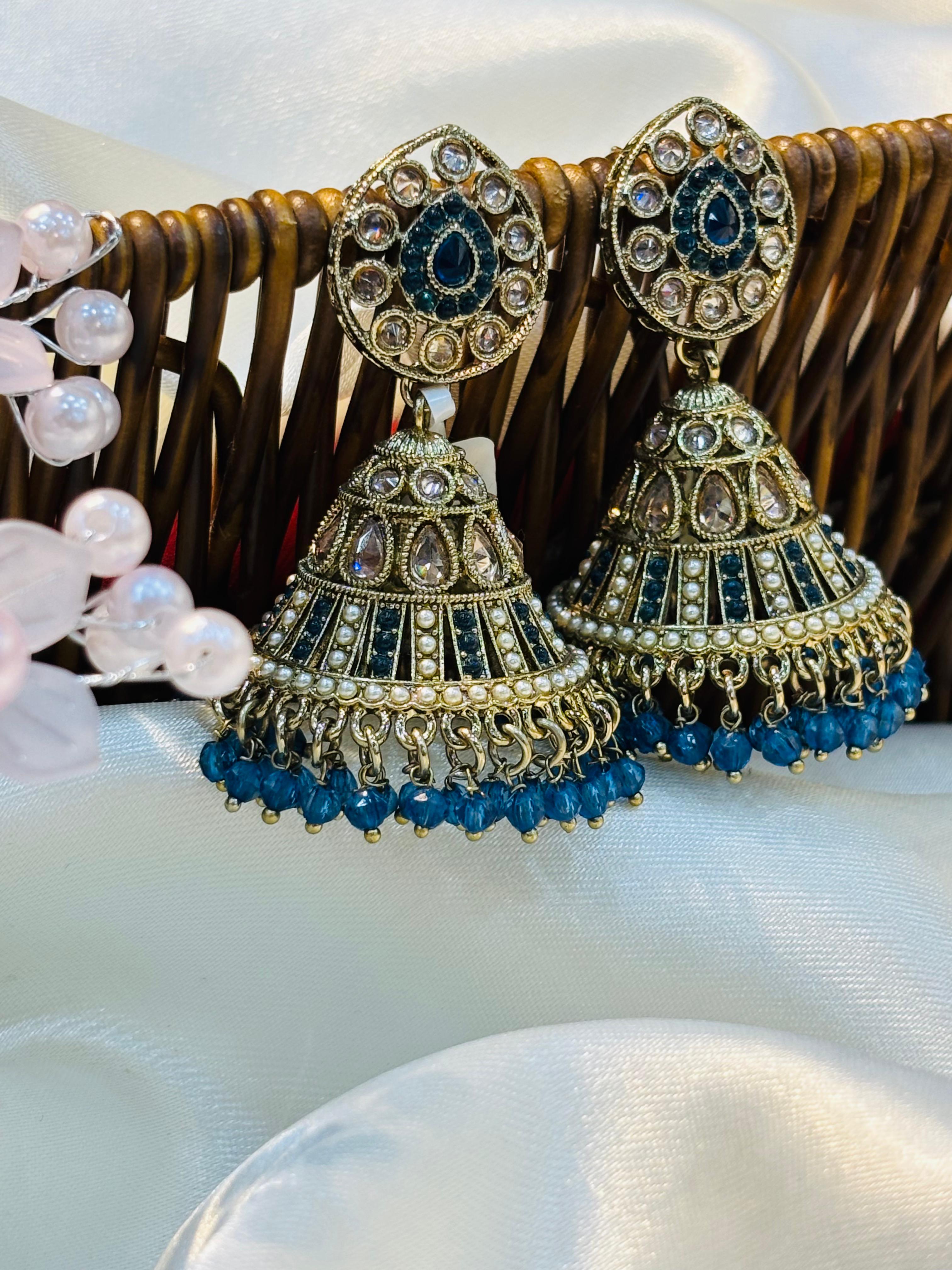 Ornate earrings with blue beads on a white surface