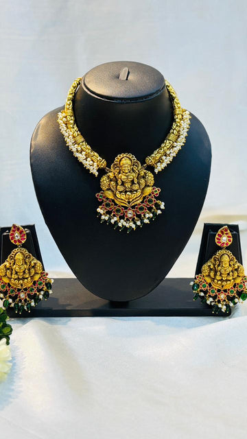 Gold necklace and earrings set on a black mannequin bust with a white background