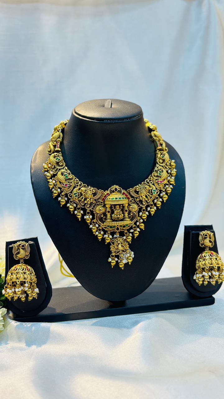 Gold necklace and earrings set on a black mannequin against a white background