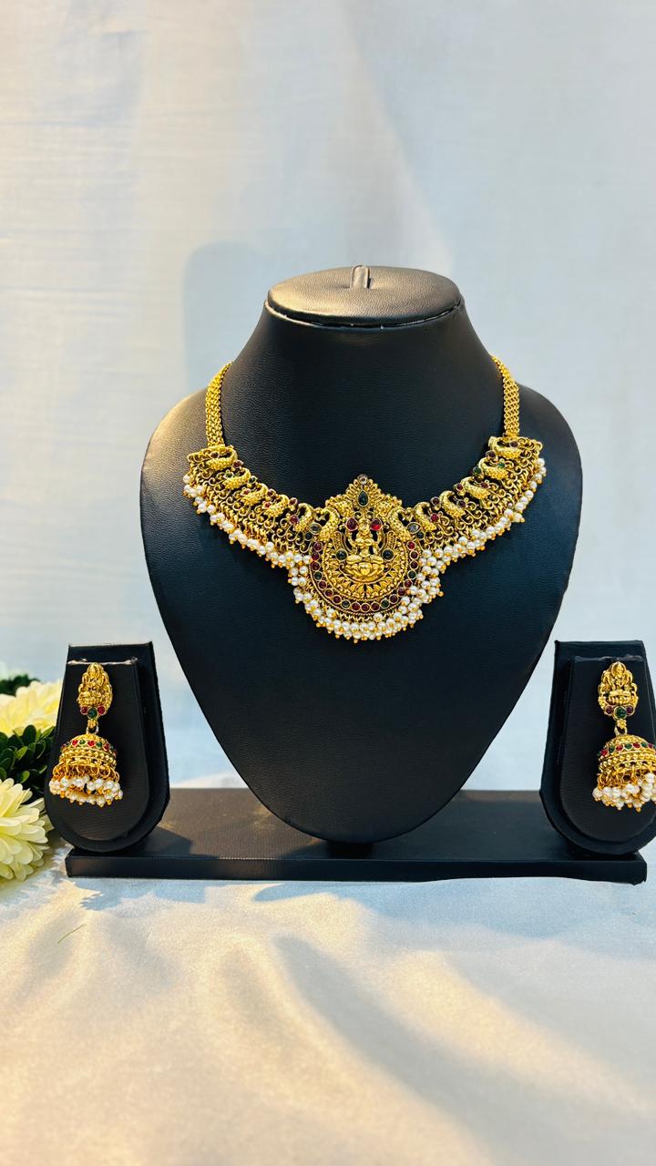 Gold necklace and earrings set on a black mannequin bust with a white background