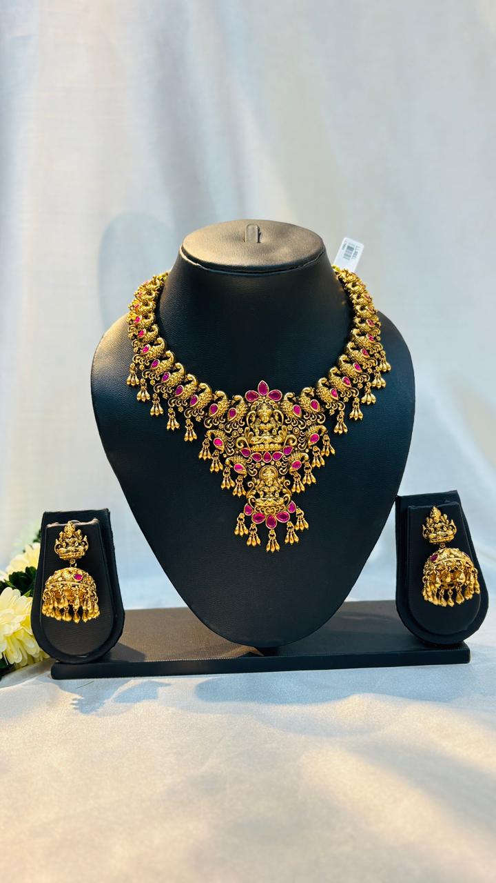 Gold necklace and earrings set on a black stand with a white background
