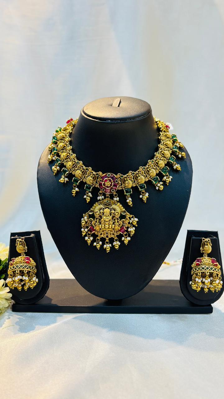 Gold necklace and earrings set on a black mannequin bust with a white background