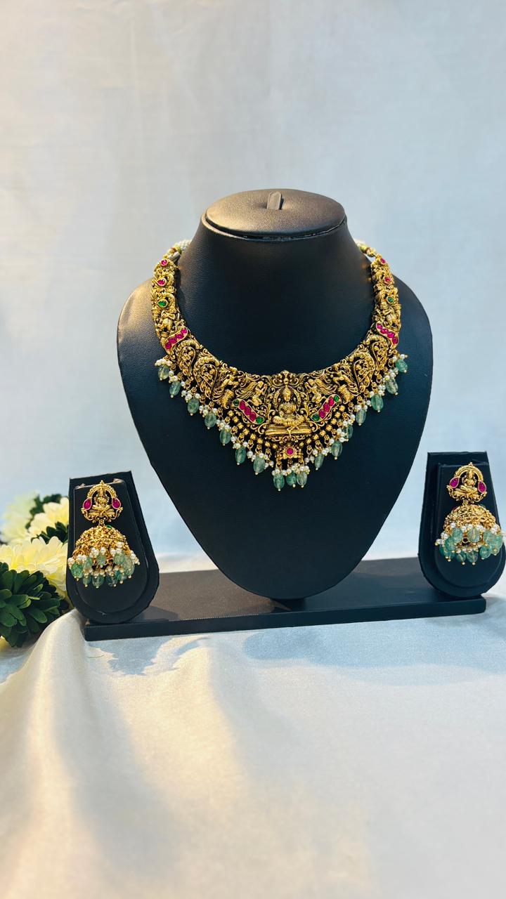 Ornate necklace set on a black mannequin bust with earrings displayed below.