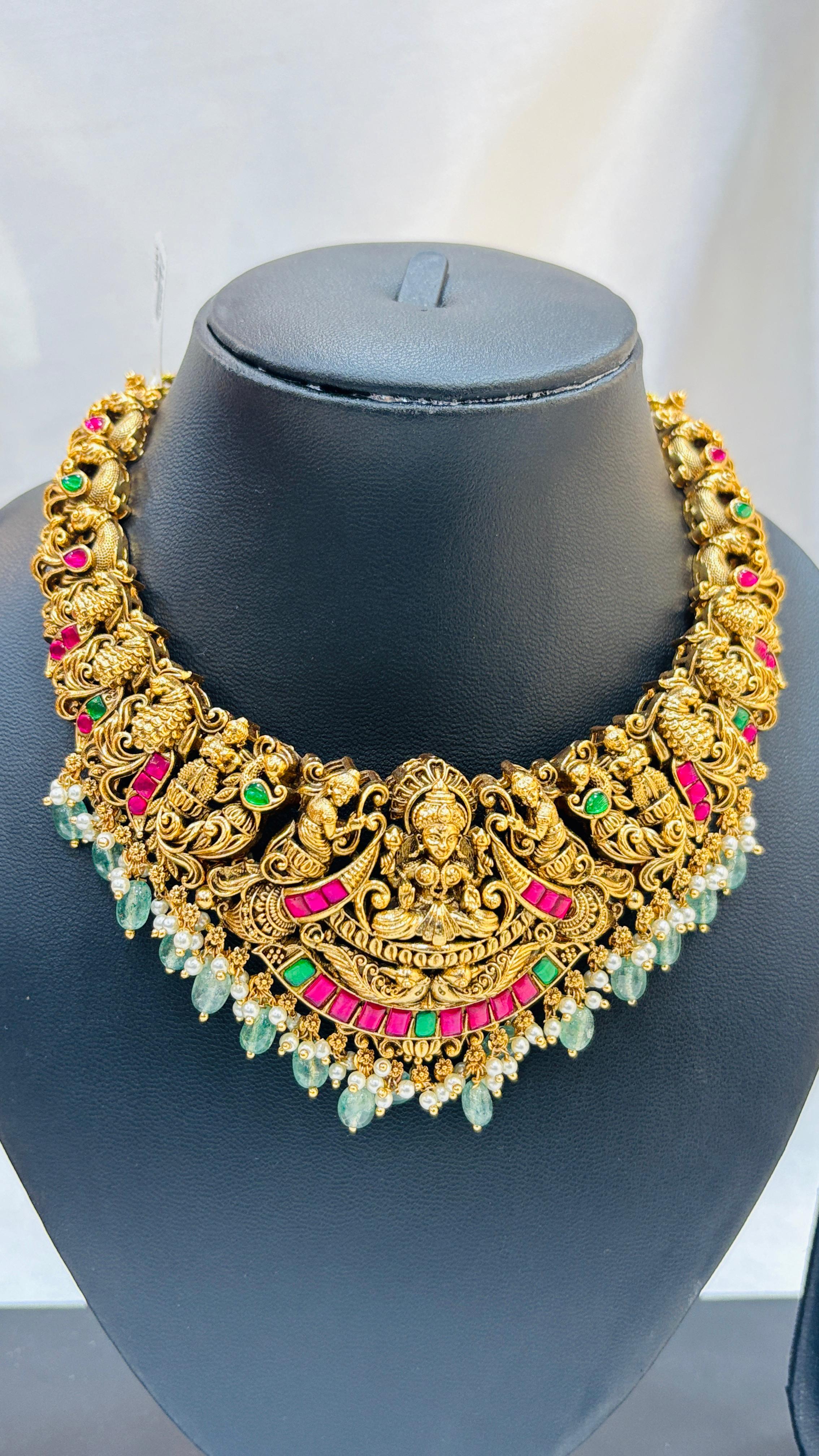 Gold necklace with colorful stones on a black mannequin bust